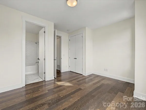 a view of an empty room with wooden floor and window