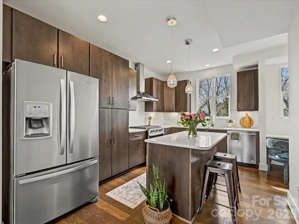 a kitchen with kitchen island a counter top space a sink stainless steel appliances and cabinets