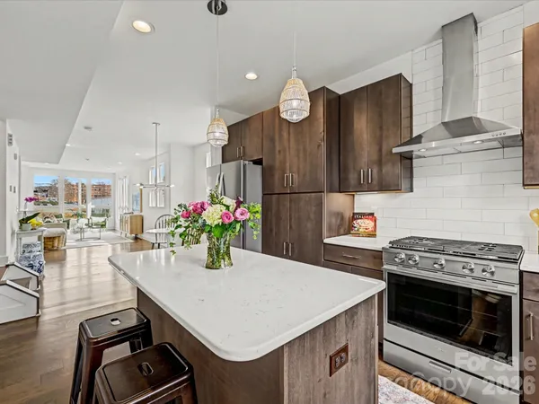a kitchen with a stove a refrigerator and a dining table with wooden floor