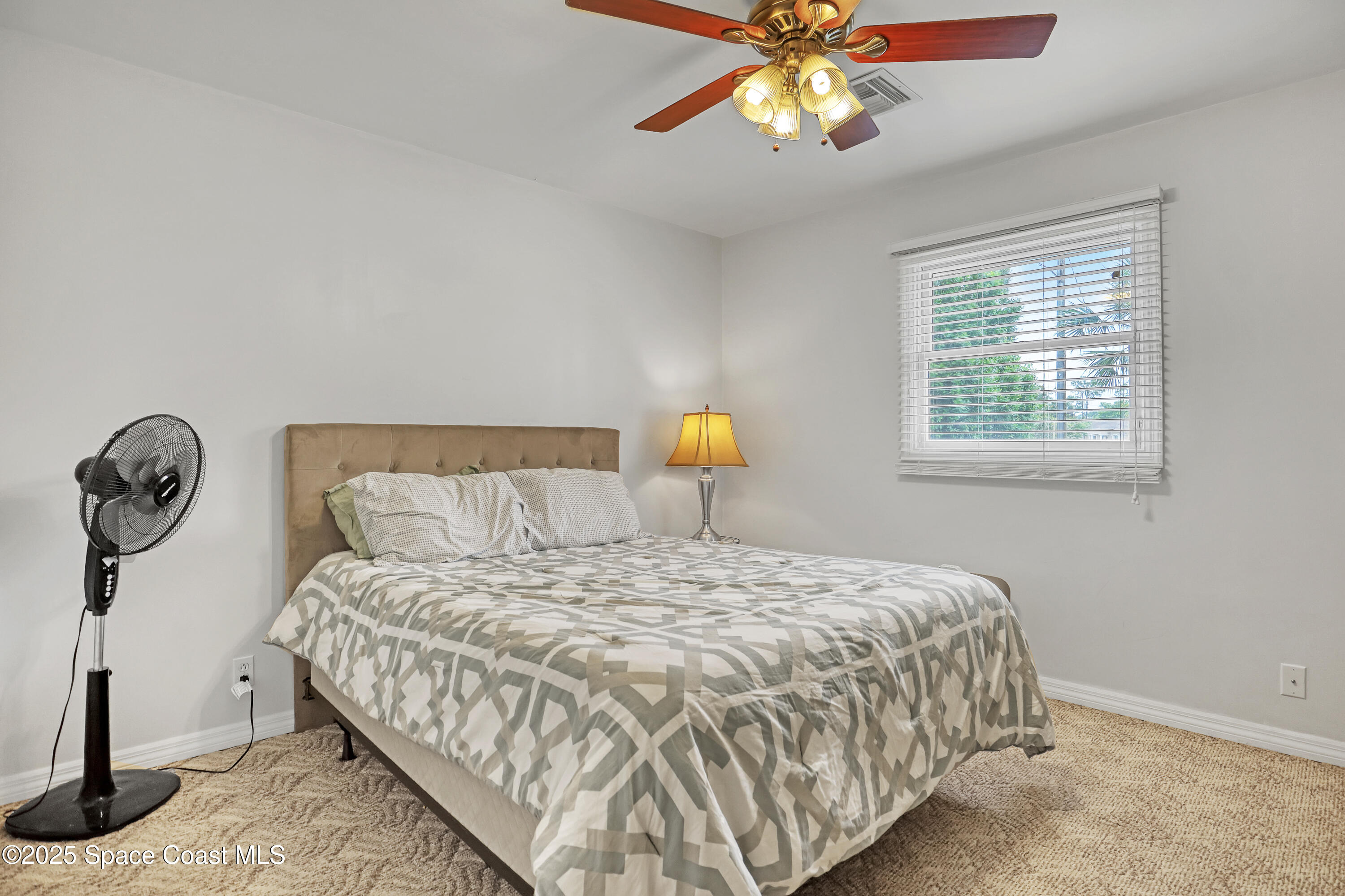 5280 Curtis Boulevard Cocoa, FL 32927 - Photo 32 of 45 a bedroom with a bed a chandelier and a window