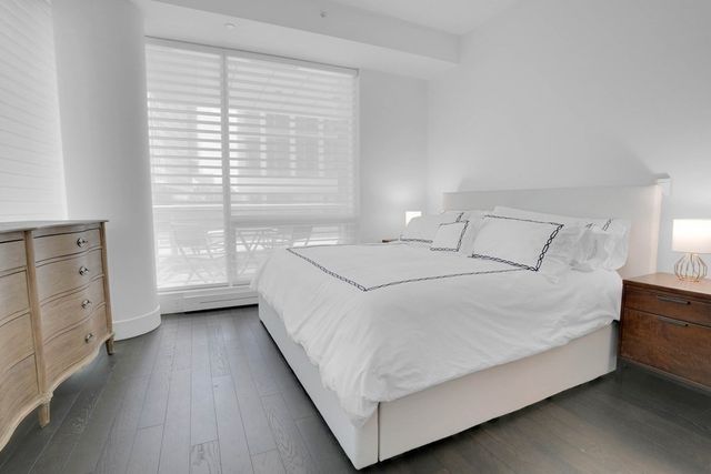 a large white bed sitting in a bedroom next to a window