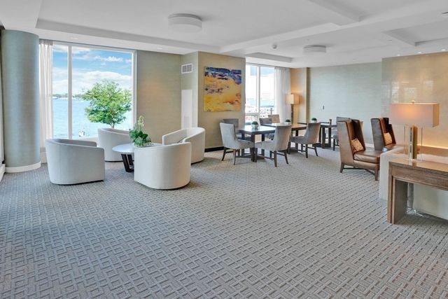 a living room with couches and kitchen view with wooden floor