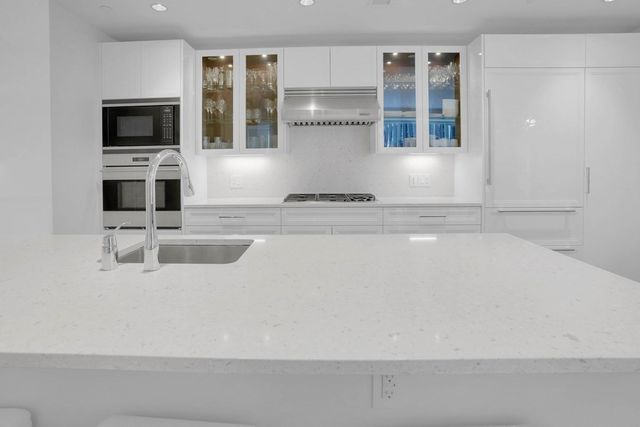 a kitchen with kitchen island a large counter top stainless steel appliances and cabinets