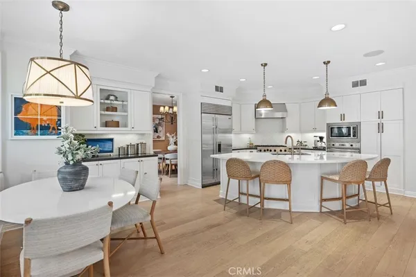 a kitchen with stainless steel appliances kitchen island granite countertop a dining table chairs and white cabinets