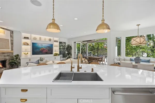 a kitchen with stainless steel appliances granite countertop a sink a stove a refrigerator and island with wooden floor