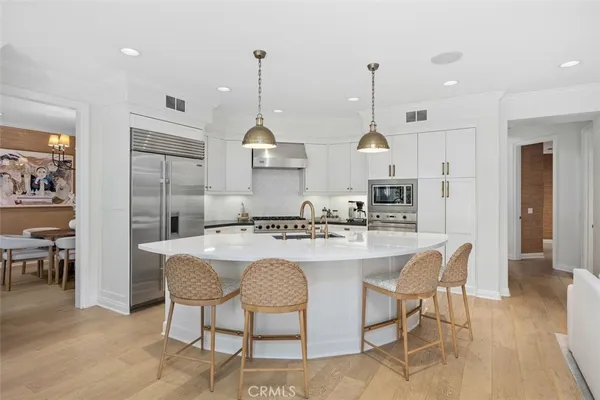 a kitchen with stainless steel appliances a stove a sink a oven a dining table and chairs