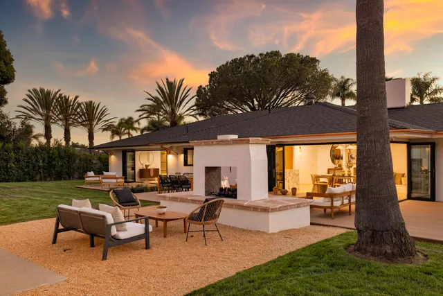 a view of a patio with couches table and chairs under an umbrella with a big yard