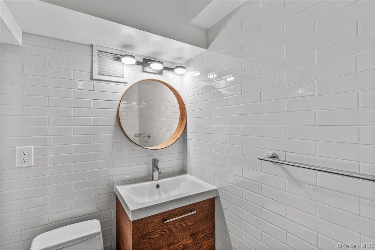 99-40 63rd Road, Unit 1Z Queens, NY 11374 - Photo 12 of 25 Half bathroom featuring tile walls, vanity, and toilet