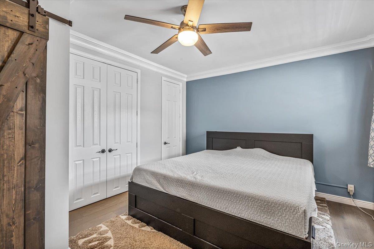 99-40 63rd Road, Unit 1Z Queens, NY 11374 - Photo 14 of 25 Bedroom featuring ornamental molding, wood finished floors, baseboards, ceiling fan, and a barn door