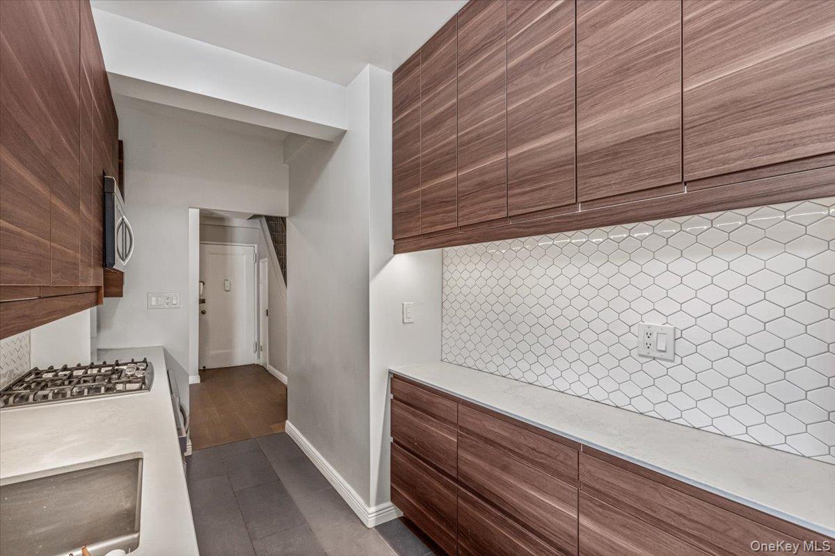 99-40 63rd Road, Unit 1Z Queens, NY 11374 - Photo 10 of 25 Kitchen with stainless steel appliances, modern cabinets, tasteful backsplash, light countertops, and brown cabinets