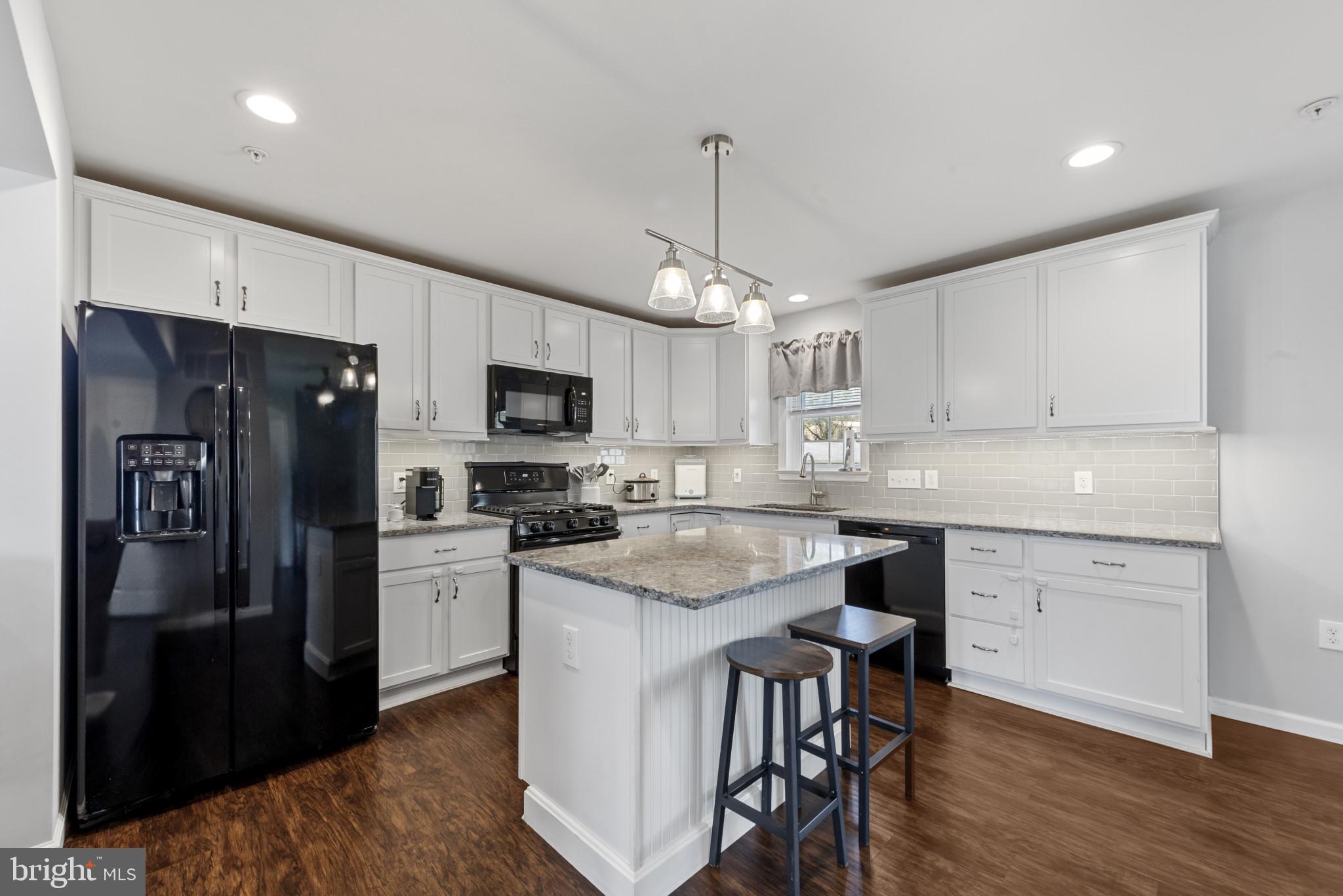 910 Rosedale Avenue Rosedale, MD 21237 - Photo 7 of 41 a kitchen with stainless steel appliances granite countertop a refrigerator a sink dishwasher a stove and white cabinets with wooden floor