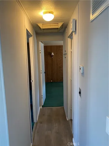 a view of a hallway with wooden floor and a bathroom