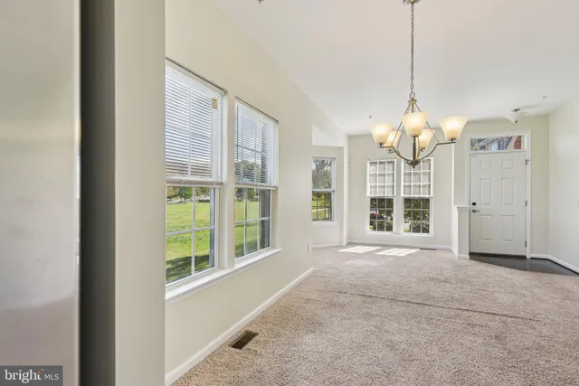 a view of an empty room with a window and chandelier