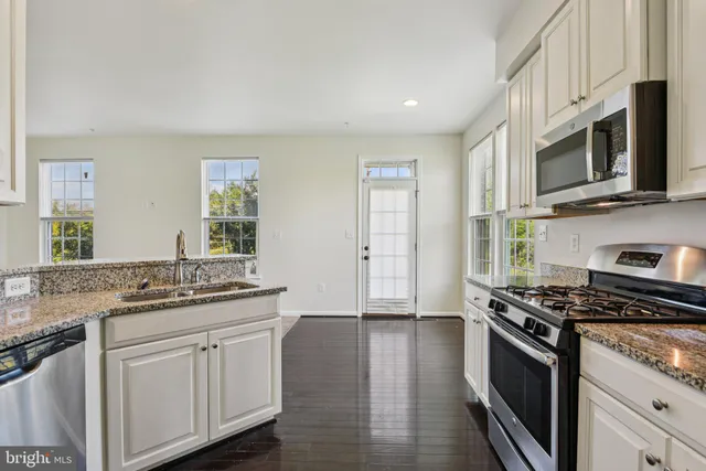 a kitchen with stainless steel appliances granite countertop a stove a sink and a microwave