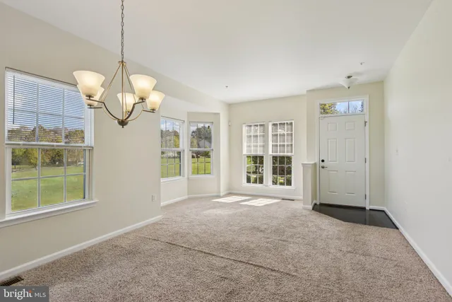 a view of a livingroom with a chandelier fan and windows