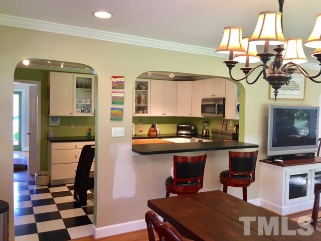 719 Beaver Dam Road Raleigh, NC 27607 - Photo 11 of 13 a kitchen with stainless steel appliances granite countertop a sink a stove top oven a chimney and a dining table