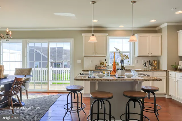 a kitchen with stainless steel appliances a dining table chairs and white cabinets next to a window
