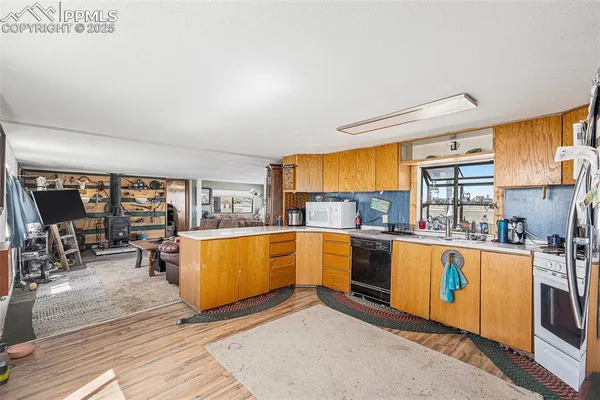 a kitchen with stainless steel appliances granite countertop a refrigerator a sink dishwasher a stove with wooden cabinets and wooden floor