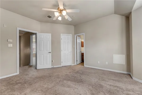 an empty room with closet and a ceiling fan