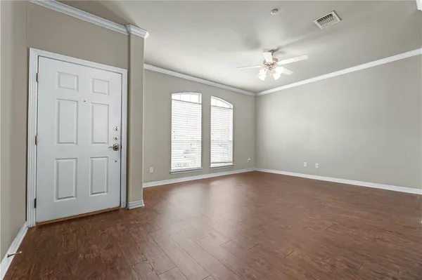 an empty room with wooden floor chandelier fan and windows