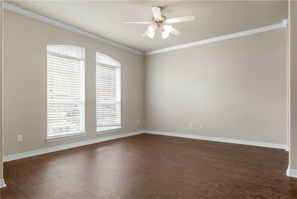 an empty room with wooden floor chandelier fan and windows