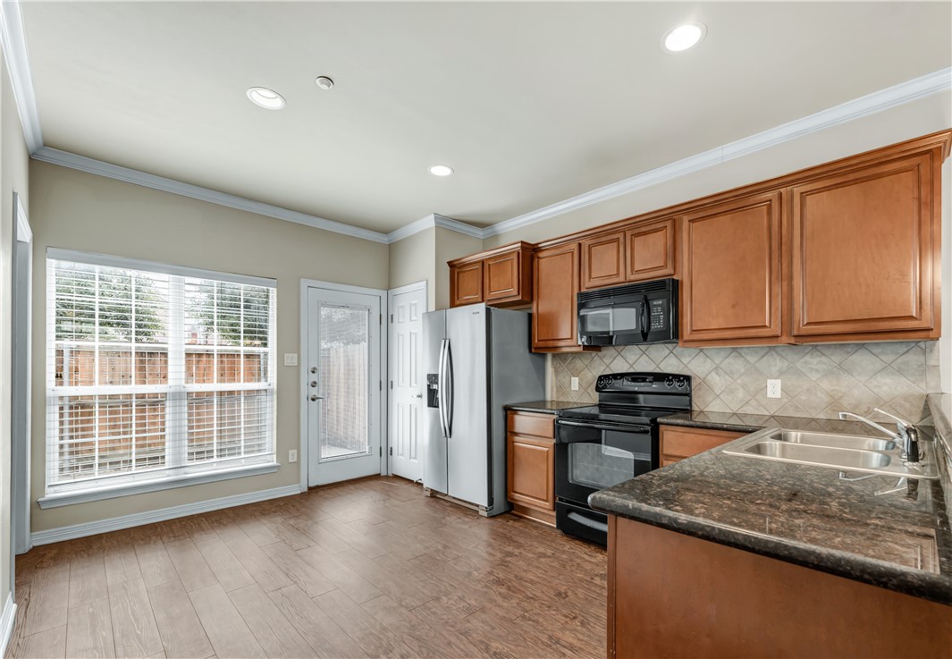 1198 Jones-Butler Road, Unit 606 College Station, TX 77840 - Photo 7 of 32 a kitchen with stainless steel appliances granite countertop a stove a sink dishwasher a microwave oven and a refrigerator with wooden floor