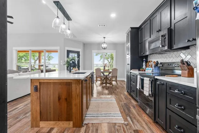 a kitchen with stainless steel appliances granite countertop lots of counter top space and wooden floor