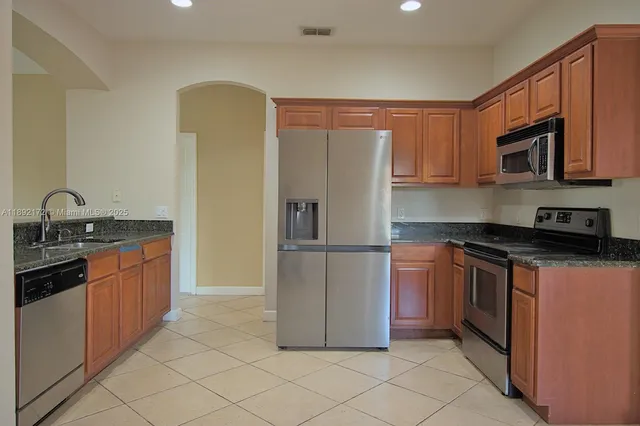 a kitchen with stainless steel appliances granite countertop a refrigerator and a sink
