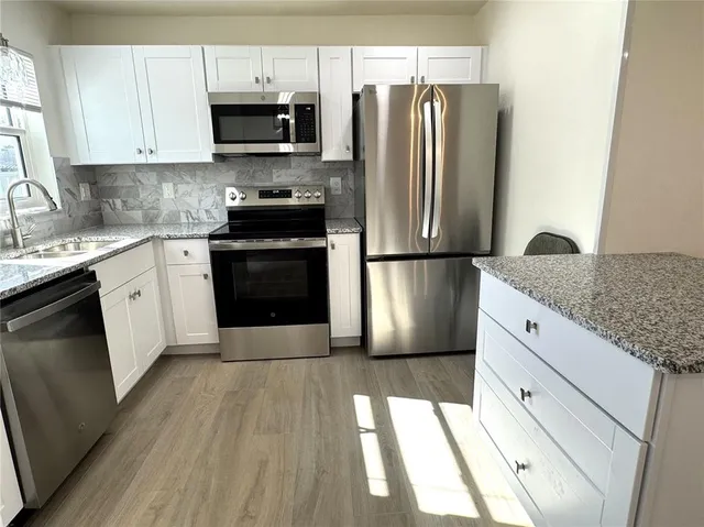 a kitchen with stainless steel appliances granite countertop a refrigerator stove a sink and a microwave