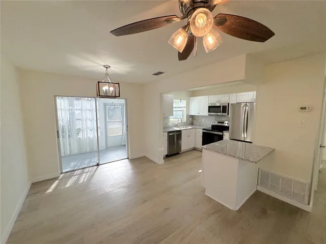 a view of a kitchen with a stove cabinets a ceiling fan and wooden floor