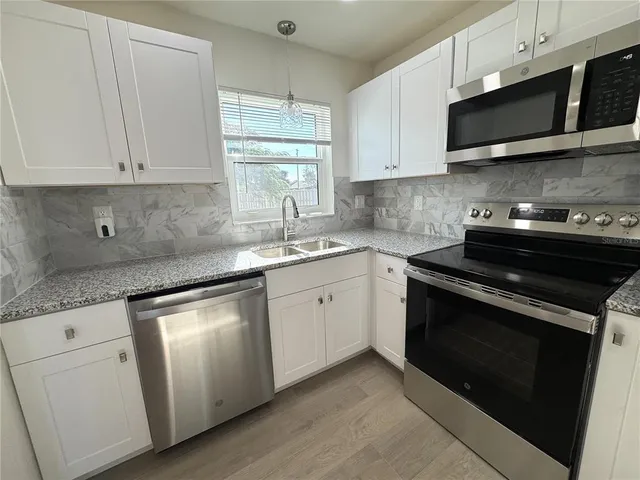 a kitchen with granite countertop white cabinets and black appliances