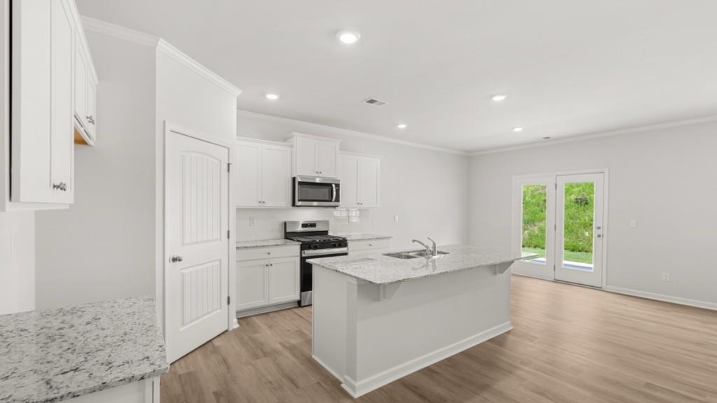 6008 Muirfield Point Union City, GA 30213 - Photo 3 of 29 a kitchen with stainless steel appliances a stove a sink a refrigerator white cabinets and wooden floor