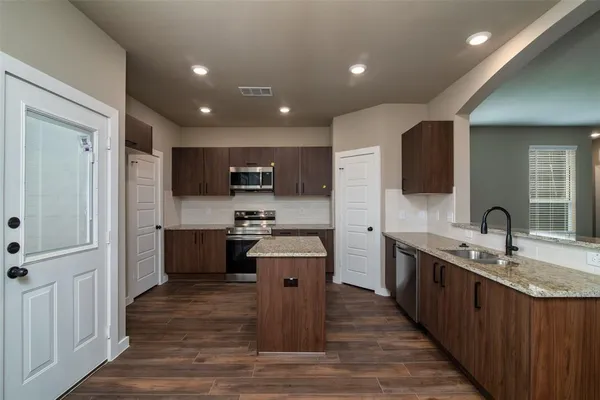 a large kitchen with stainless steel appliances lots of counter space and wooden floor