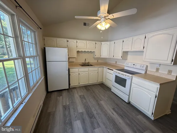 a kitchen with a white cabinets a sink dishwasher and a stove with wooden floor