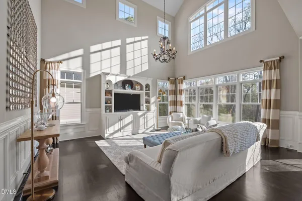 a living room with furniture large window and wooden floor