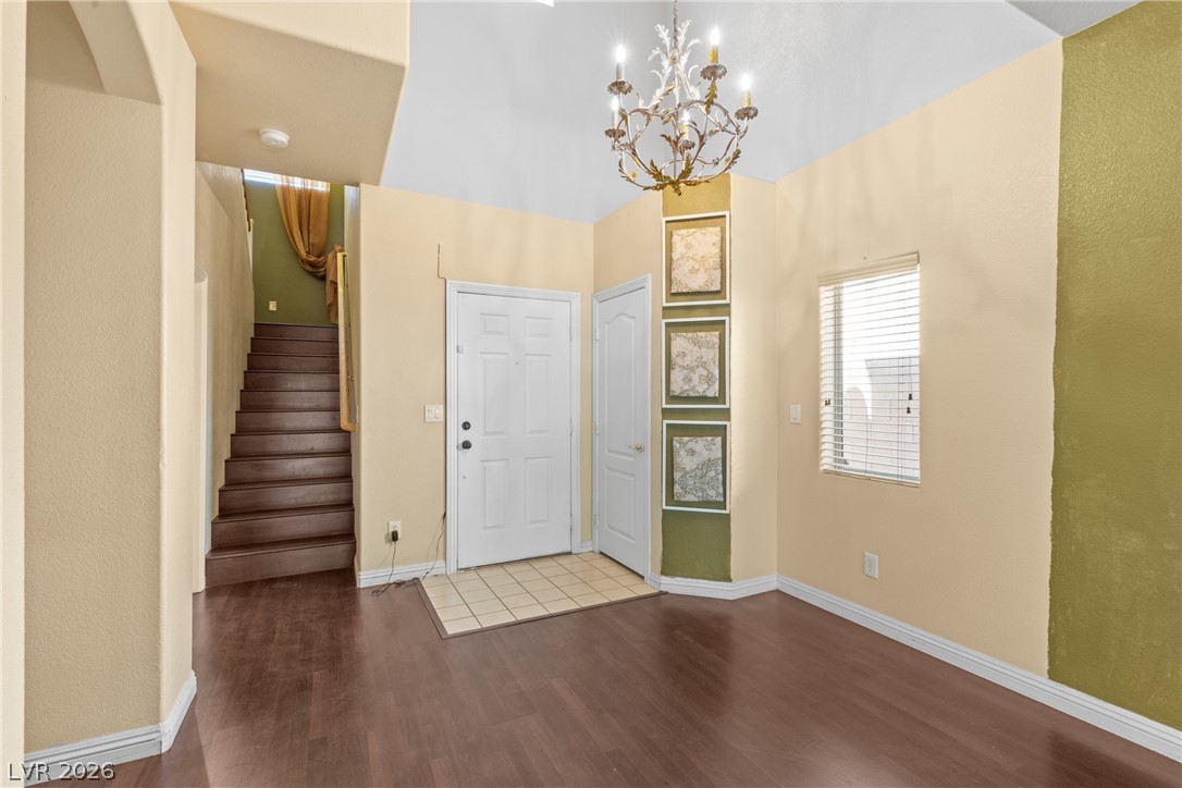 8934 Deep Ridge Court Las Vegas, NV 89178 - Photo 5 of 47 Enter into a welcoming foyer, featuring warm wood flooring and a grand chandelier illuminating the entryway.