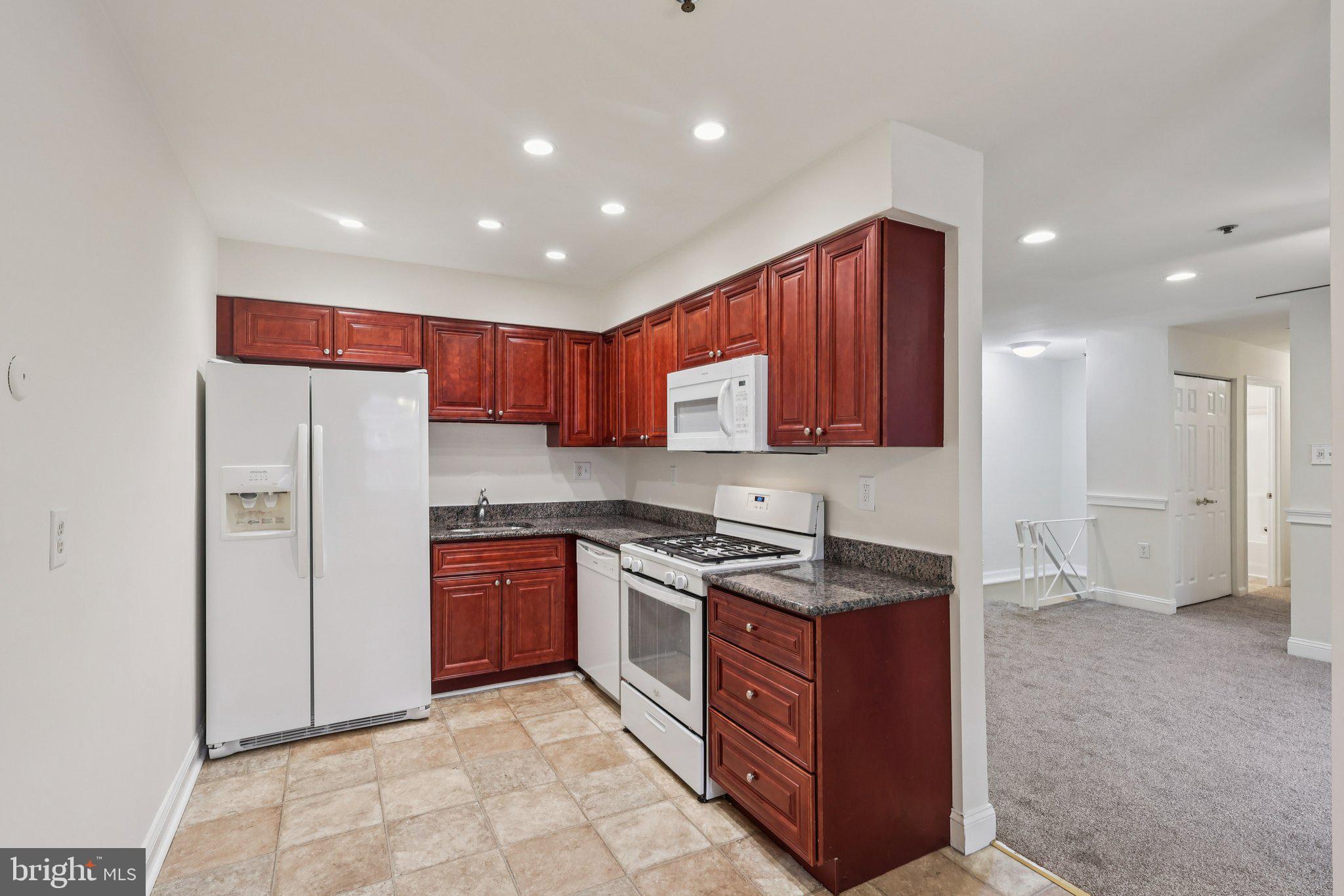 1600 Church Road, Unit C111 Wyncote, PA 19095 - Photo 6 of 24 a kitchen with stainless steel appliances granite countertop wooden cabinets a stove a sink and a refrigerator