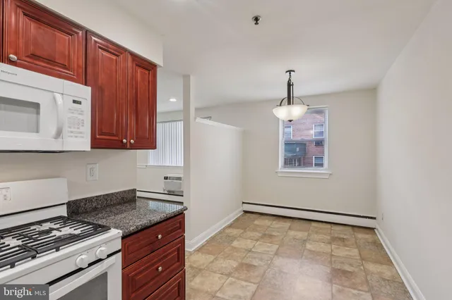 a kitchen with granite countertop a stove and a wooden cabinets