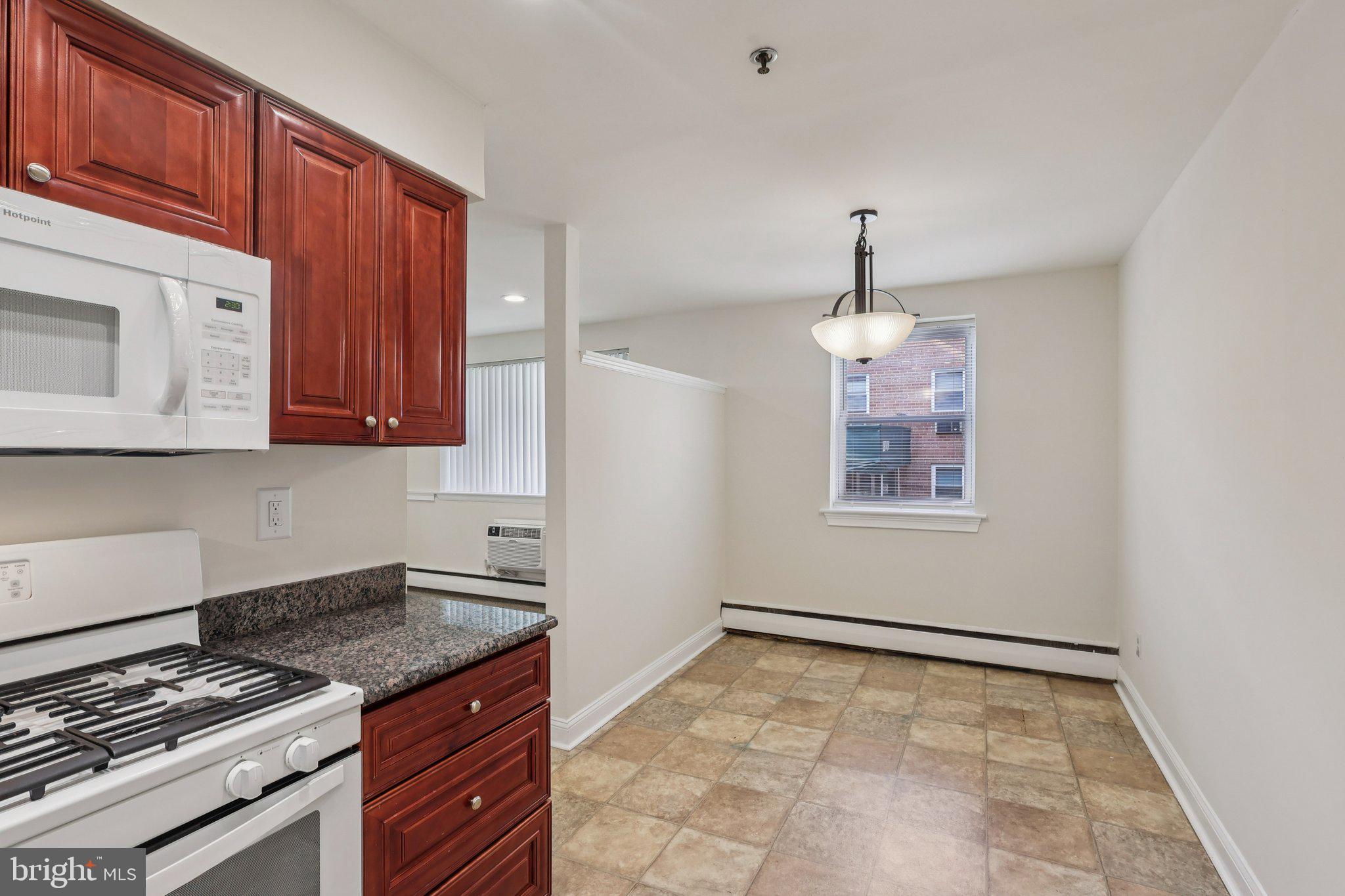 1600 Church Road, Unit C111 Wyncote, PA 19095 - Photo 7 of 24 a kitchen with granite countertop a stove and a wooden cabinets