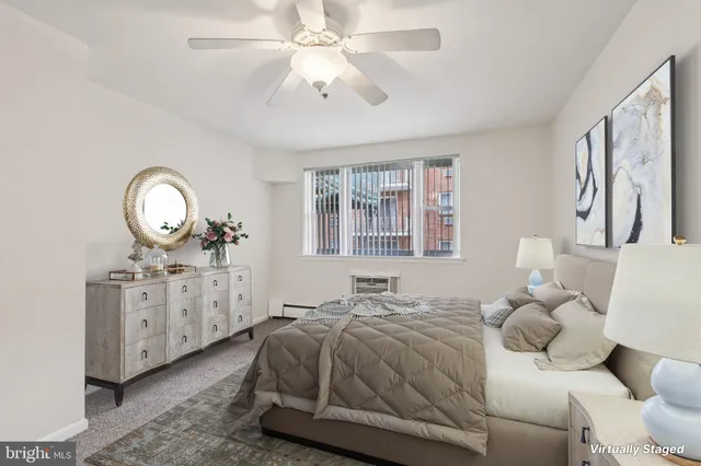 a spacious bedroom with a bed a chandelier dresser and mirror