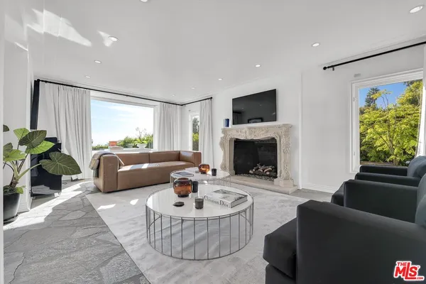 a living room with furniture a large window and a fireplace