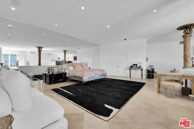 a large white kitchen with a stove a sink a counter top space and living room view