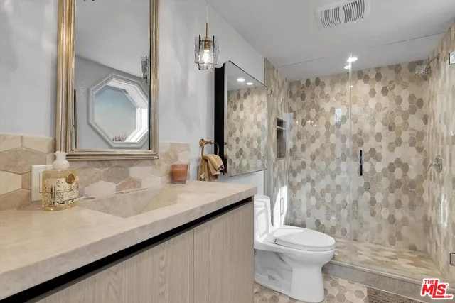 a bathroom with a granite countertop sink a toilet and a mirror