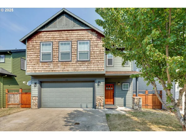 a view of a house with a yard and large tree