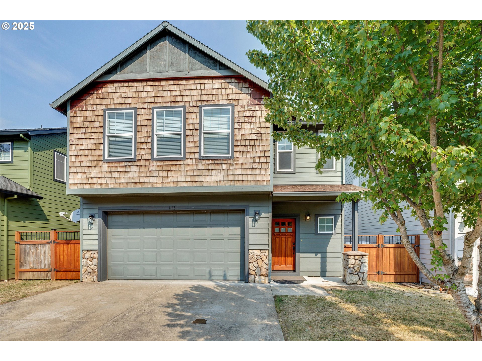a view of a house with a yard and large tree