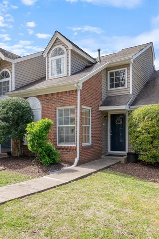 a view of a brick house with plants and large windows