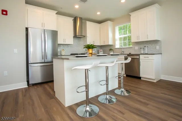 a kitchen with a refrigerator a stove a sink and wooden floor