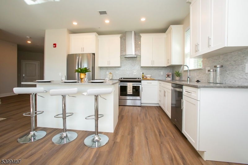 74 Passaic Avenue, Unit 107 Fairfield, NJ 07004 - Photo 3 of 13 a large kitchen with stainless steel appliances granite countertop a sink a stove a dining table and chairs