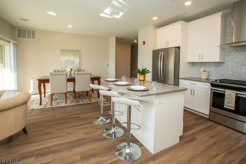 74 Passaic Avenue, Unit 107 Fairfield, NJ 07004 - Photo 6 of 13 a kitchen with stainless steel appliances kitchen island granite countertop a stove a sink a refrigerator and white cabinets with wooden floor