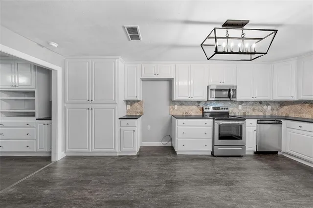 a kitchen with cabinets stainless steel appliances and a chandelier
